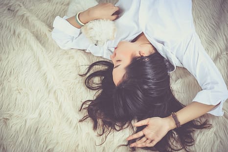  5 natural ways to improve sleep, woman with long dark hair sleeing in a bed