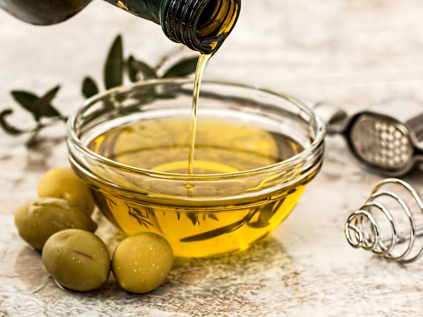 olive oil in bowl and green olives in front