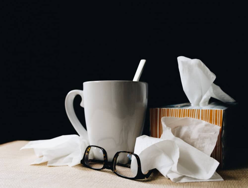glasses, tissues and cup of tea with a spoon on a table