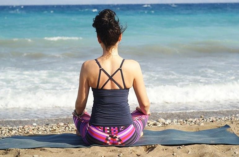 woman meditating sitting on a beach
