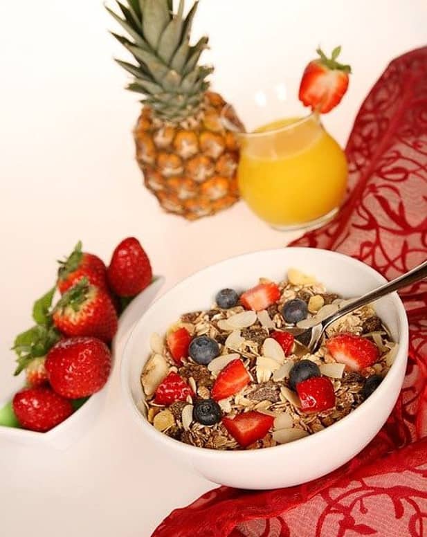 a bowl with fruit and seeds, and nuts, pineapple, strawberries, blue berries